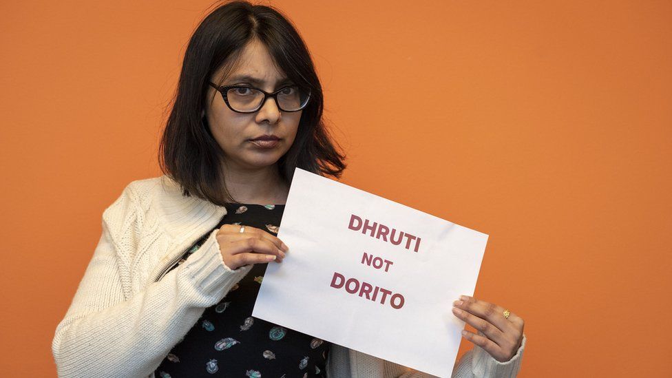 Dhruti Shah holding a picture saying "Dhruti not Dorito"