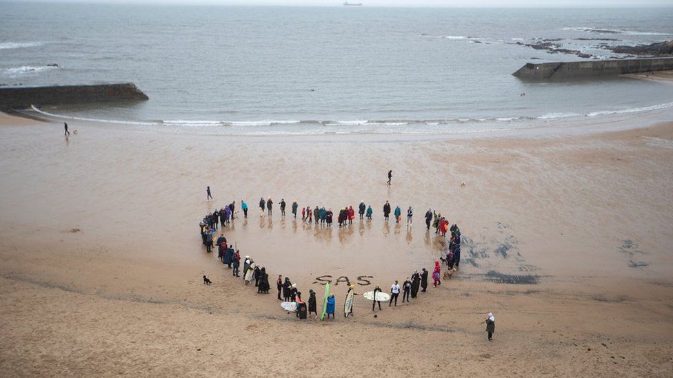 People form a heart shape on the beach