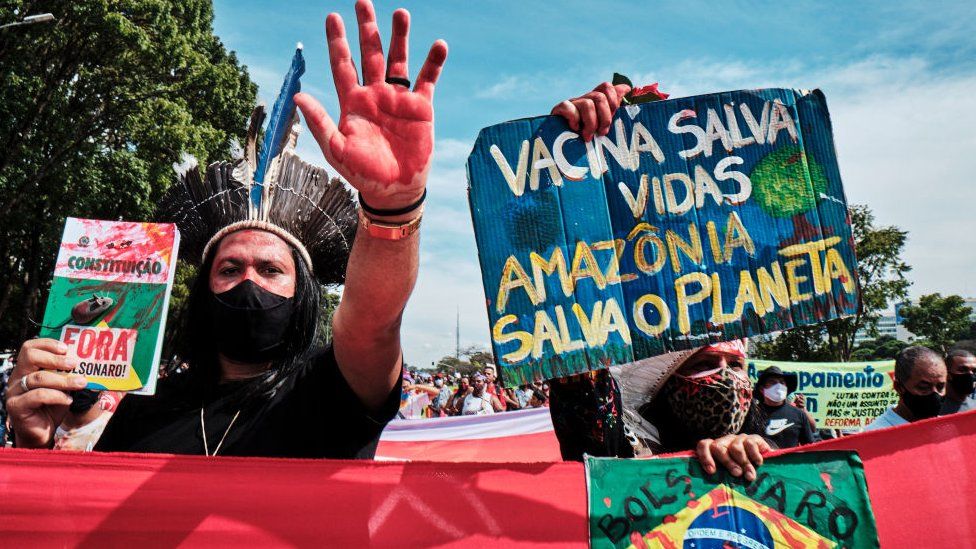 Demonstrators hold signs during a protest against President Jair Bolsonaro in Brasilia on May 29, 2021