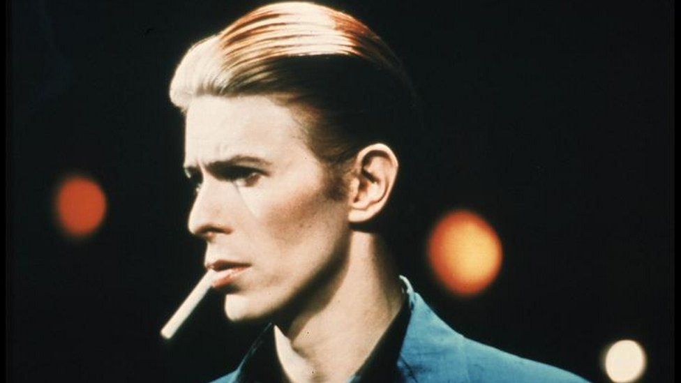 David Bowie with a cigarette in his mouth, pictured in 1976