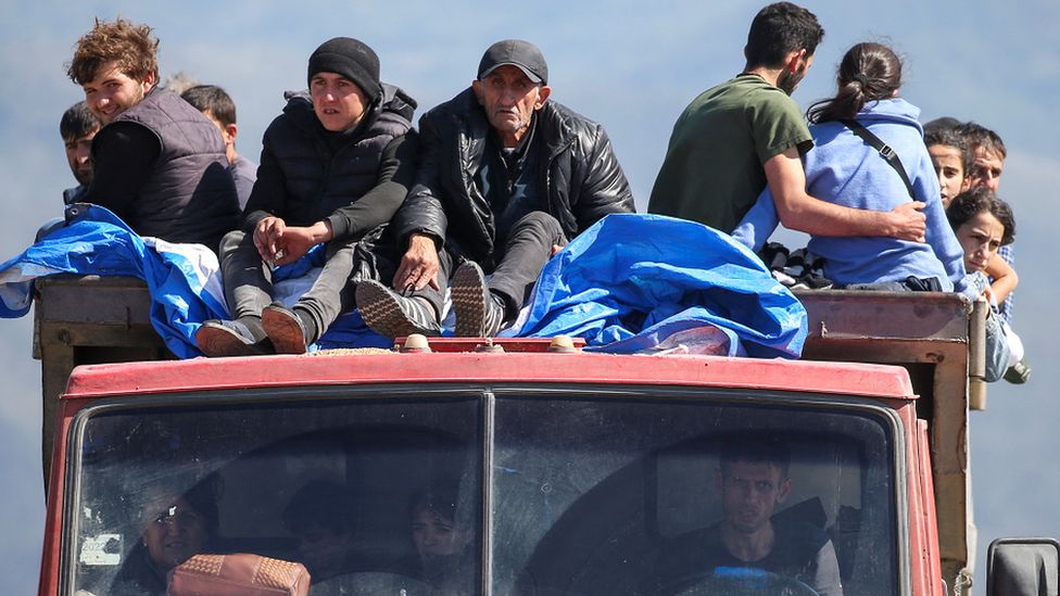 Refugees from Nagorno-Karabakh region ride in a truck upon their arrival at the border village of Kornidzor, Armenia, on 27 September