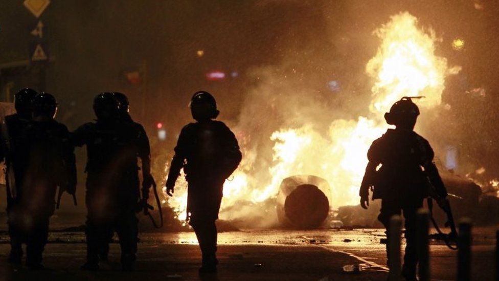 Police walk in front of a burning barricade in Bucharest, Romania. Photo: 10 August 2018