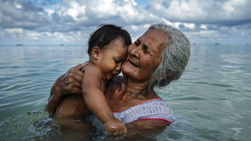 Woman holding child in sea