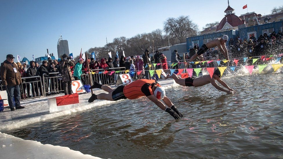 Os participantes saltam para a Ã¡gua gelada do Rio Songhua durante uma competiÃ§Ã£o de nataÃ§Ã£o de inverno no Festival Internacional de Esculturas de Gelo e Neve de Harbin, em Harbin, provÃ­ncia de Heilongjiang, China, 05 de janeiro de 2019. Cerca de 600 nadadores de inverno participaram da competiÃ§Ã£o.