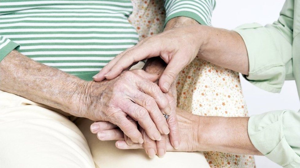 Elderly woman being comforted by a carer