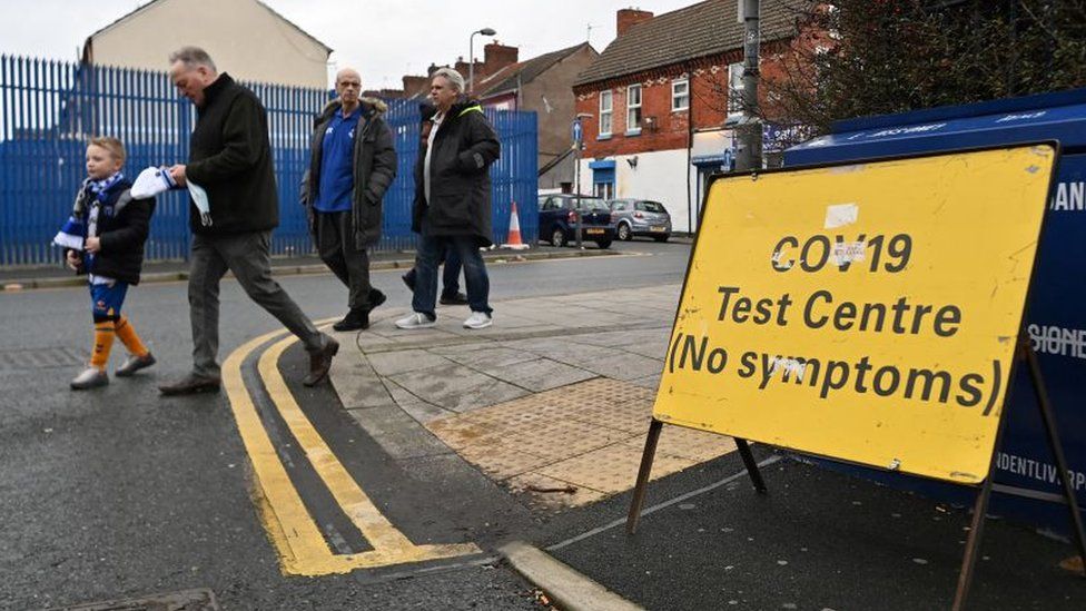 People walking past a Covid testing sign on their way to Everton's Goodison Park stadium in Liverpool