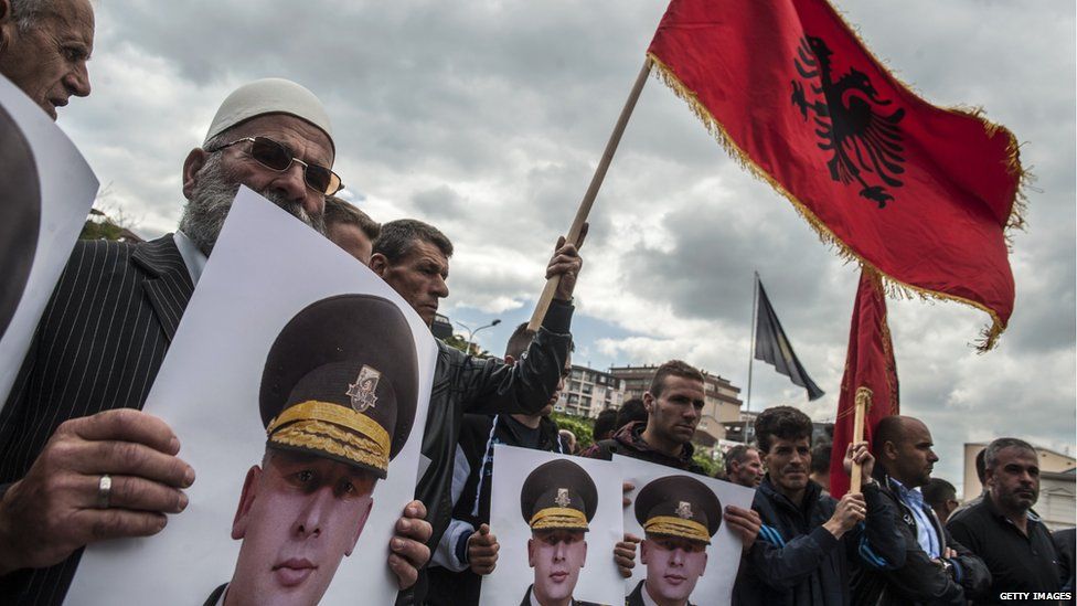 Kosovan protesters wave the Albanian flag and hold portraits of former Kosovo Liberation Army commander Sylejman Selimi during a demonstration in front of Kosovo's parliament on 29 May 2015
