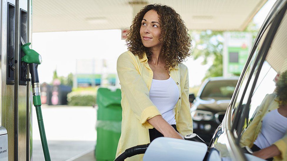 Woman filling up car at petrol pump