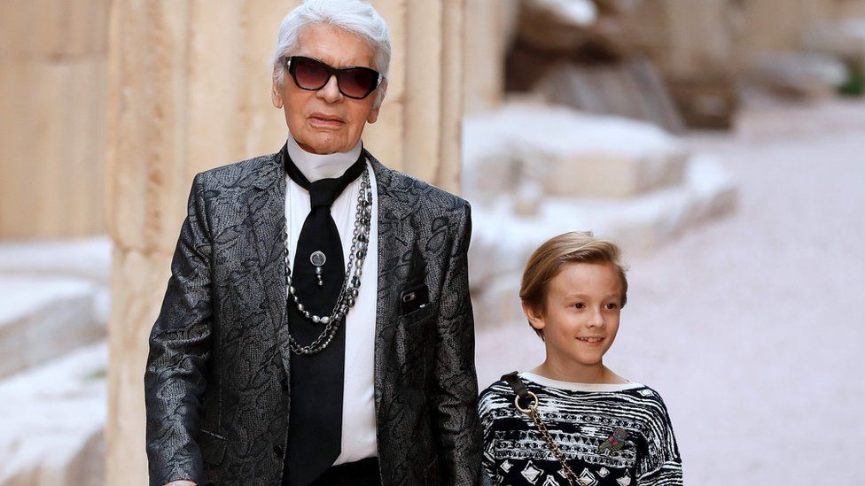 In this file photo taken on May 3, 2017 German fashion designer Karl Lagerfeld acknowledges the audience with his godson Hudson Kroenig at the end of his Chanel Croisiere (Cruise) fashion show at the Grand Palais in Paris