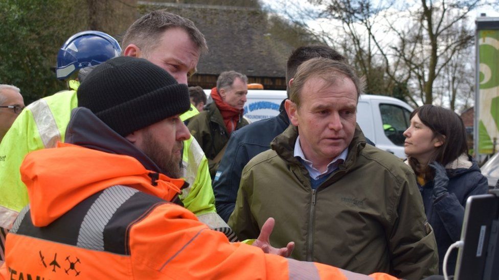 George Eustice views a screen showing drone camera images of flood defences during a visit to Ironbridge in Shropshire
