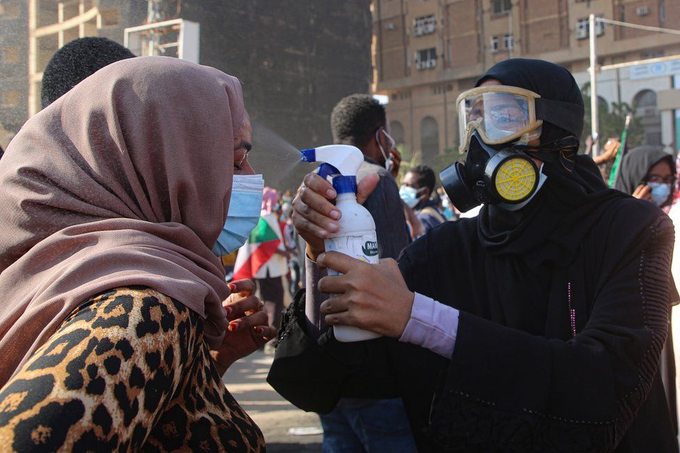 A Sudanese female protestor helps to another one who affected from tear gas as they clash with security forces during protest in front of the main door of the Republican Palace in the capital Khartoum, Sudan, 19 December 2021. Tens of thousands of protesters marched during a demonstration marking the third anniversary of the start of mass demonstrations that led to the ousting of the dictator al-Bashir.