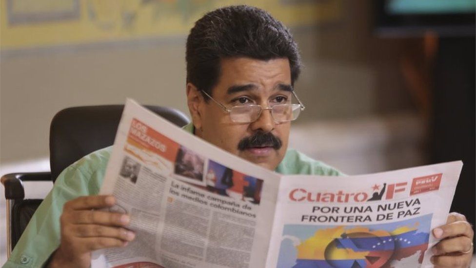 Nicolas Maduro reads a pro-government newspaper as he speaks during his weekly broadcast "In contact with Maduro" in Caracas on 15 September, 2015.