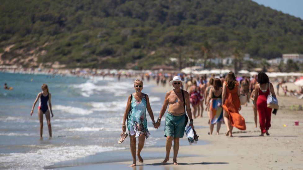 People walking along a beach in Ibiza