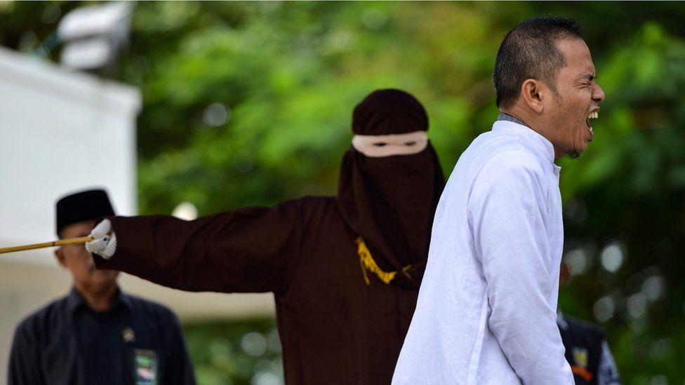 Aceh Ulema Council (MPU) member Mukhlis reacts as he is whipped in public by a member of the Sharia police in Banda Aceh on October 31, 2019