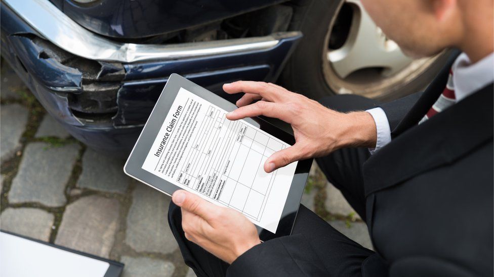 Man holding tablet examining damaged car