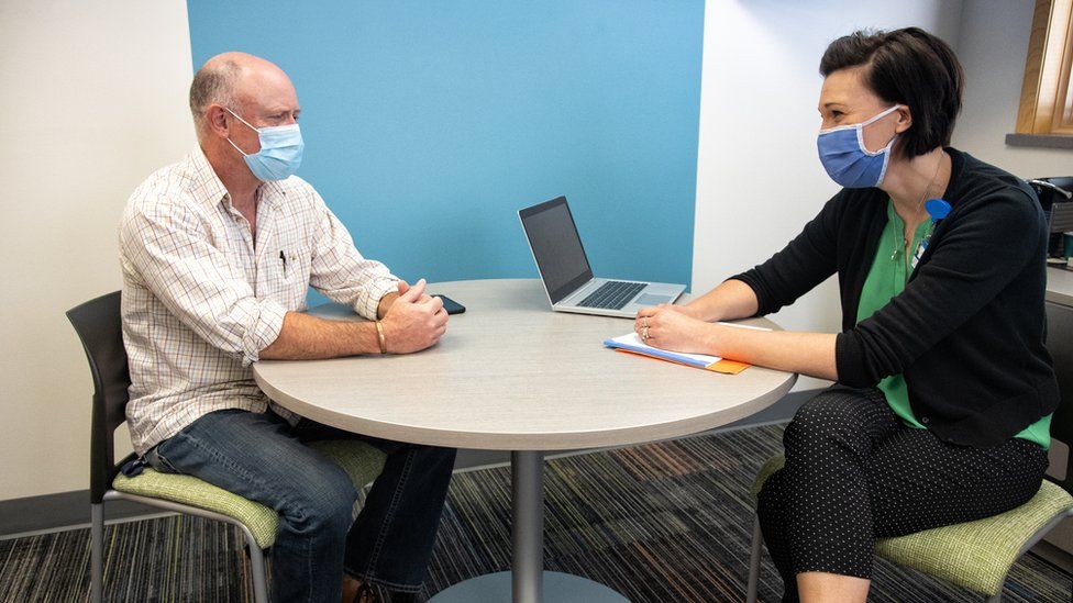 Therapist seeing patient, both wearing masks