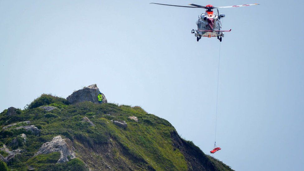 A Coastguard Rescue helicopter is seen during the rescue of an injured person at the bottom of the cliffs at Portland in July 2021