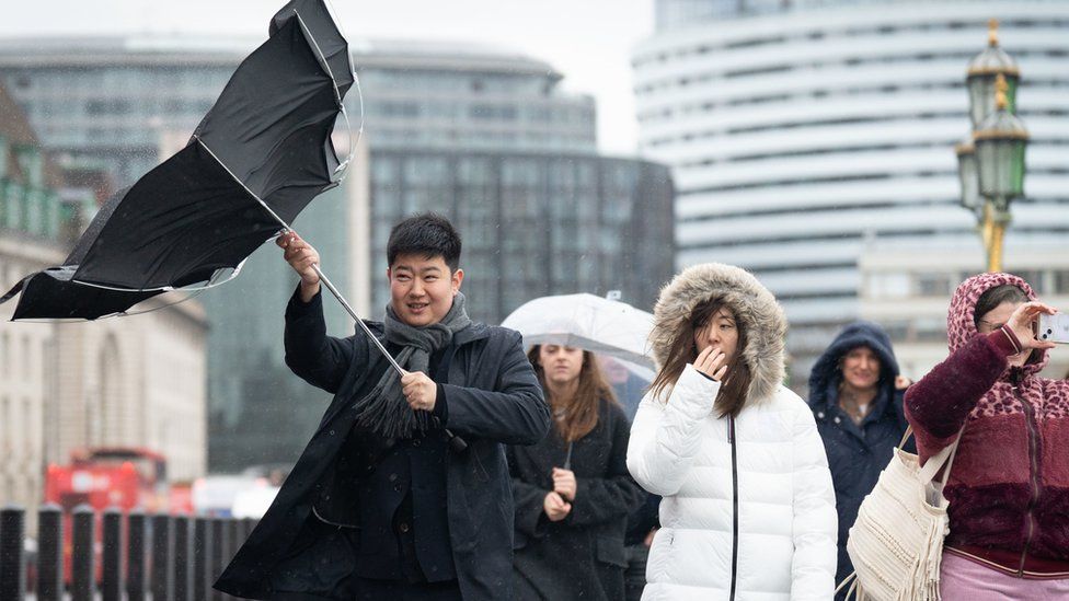 A person's umbrella is blown inside out during heavy rain on Westminster Bridge (file photo)