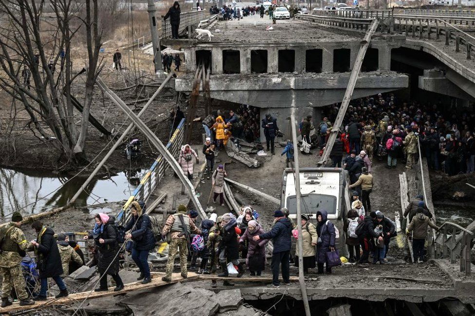 People cross a destroyed bridge as they evacuate the city of Irpin, 5 March 2022