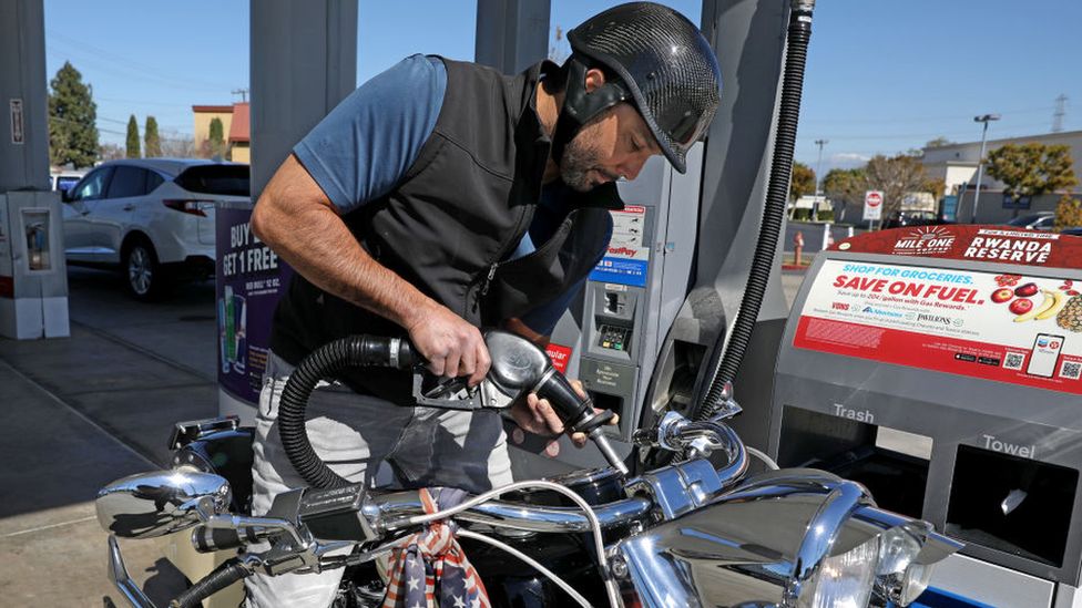 Мужчина заправляет велосипед на заправочной станции в США