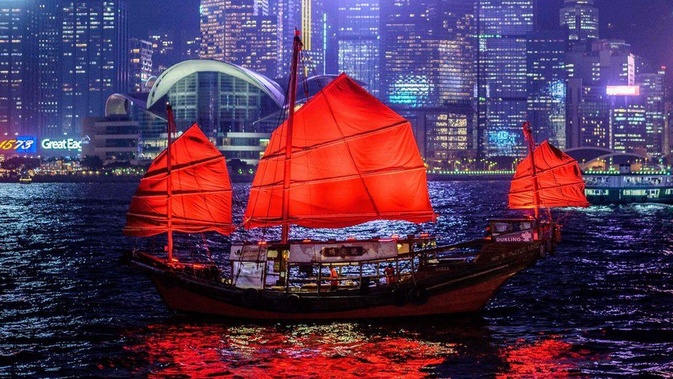 A traditional wooden tourist junk boat sails in the waters of Victoria Harbour in Hong Kong.