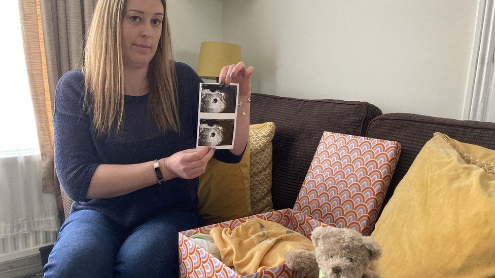 Lucy Mills holding a printout of a pregnancy scan