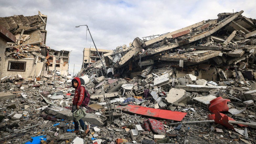 A Palestinian boy walks past destroyed buildings in the central Gaza Strip (28 November 2023)