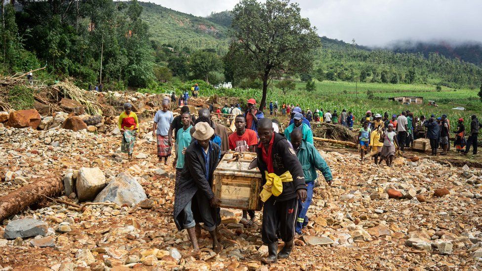 Wooden graves are carried along a makeshift path