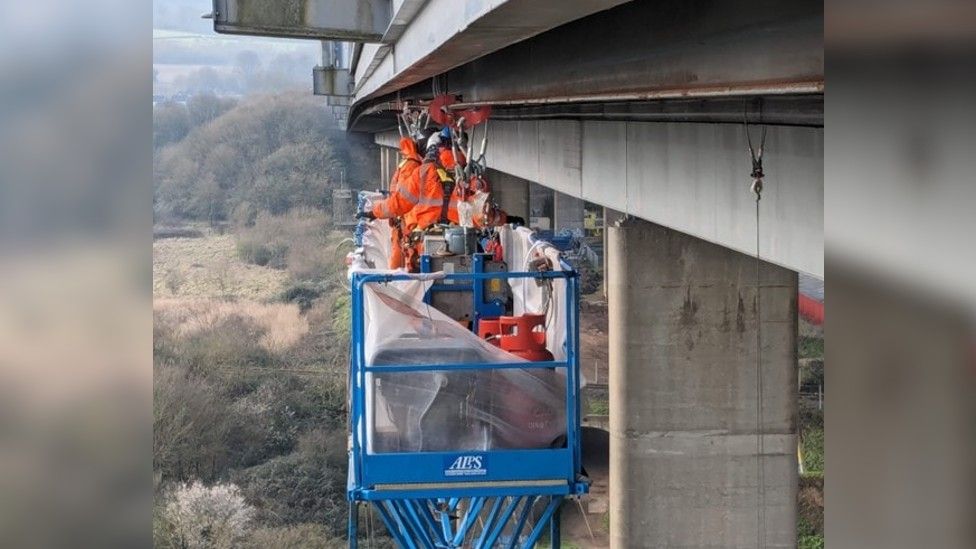 Inspection work takes place on a runway beam under the bridge parapets