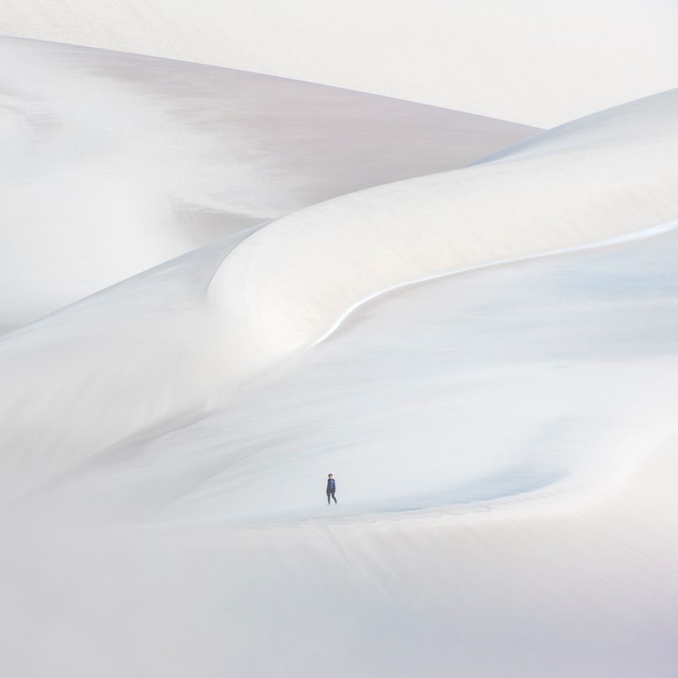 A lone walker on a white sand dune at La Puna, Argentina.