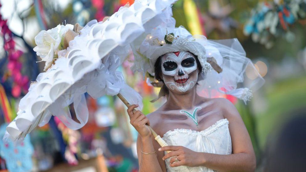 A woman in skeleton make-up carries and umbrella