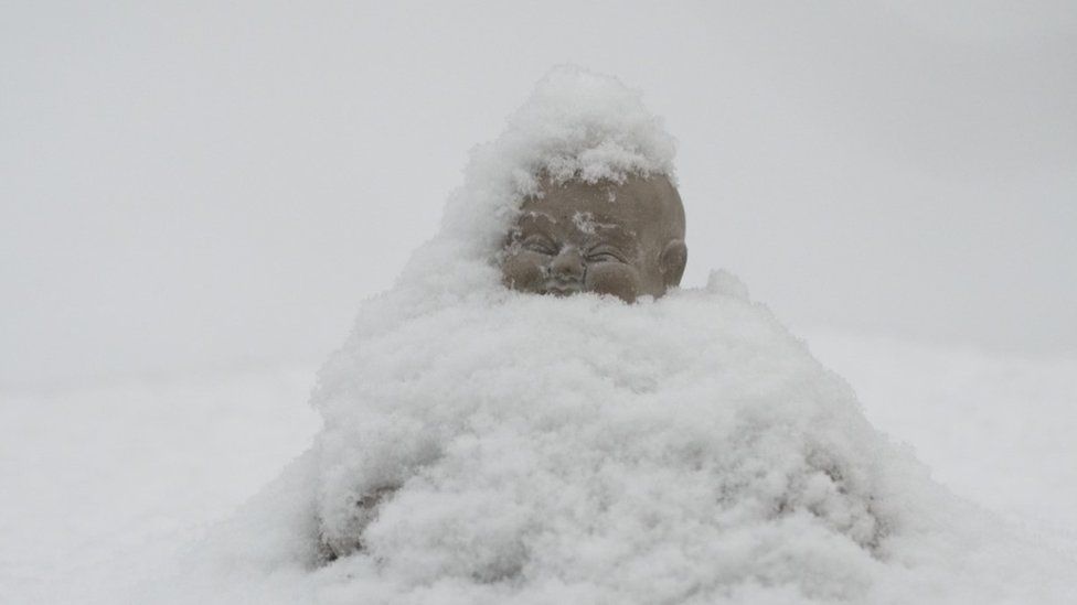 A snow-covered Buddha ornament in Buxton, Derbyshire