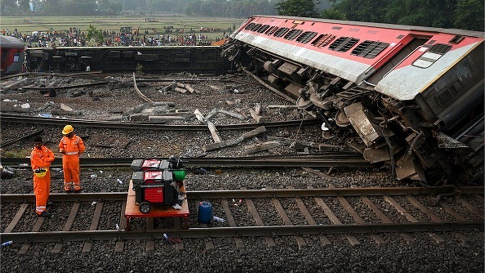 A rescue worker walks next to a train wreck during the search for survivors at the accident site of a three-train collision near Balasore,