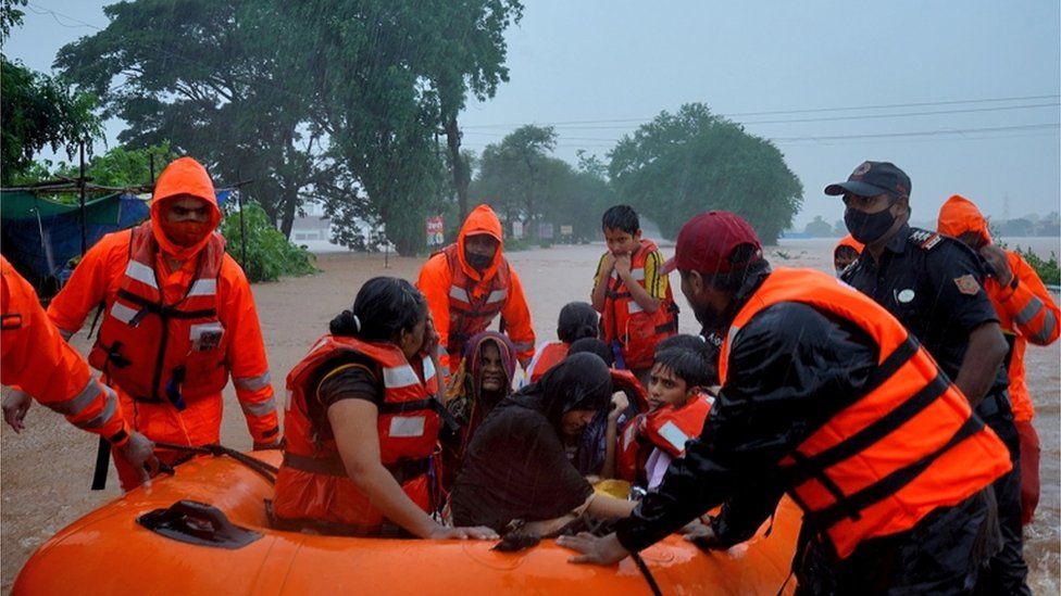 Rescuers carry resident from flooded areas in a dinghy, western India, July 2021