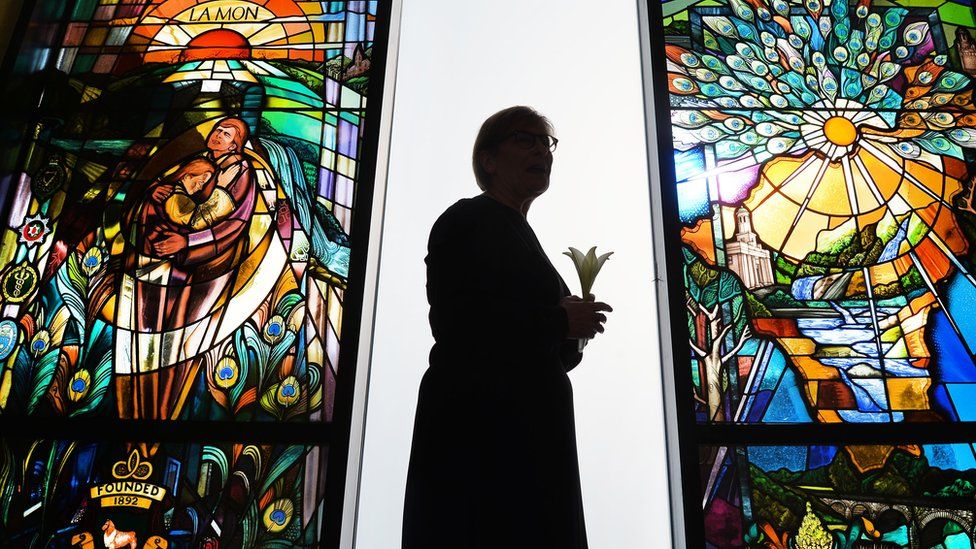 The stained glass memorial window the a woman standing holding a lily