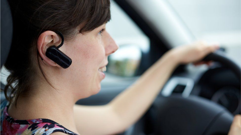 Woman talking in a car with phone headset
