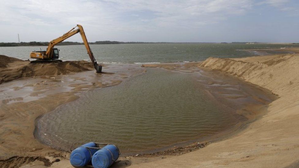 A machine works on the mouth of Rio Doce to enlarge its connection with the sea in Regencia village