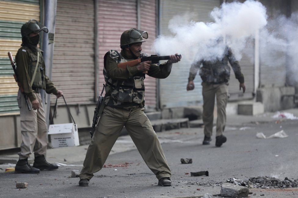 An Indian Paramilitary soldier fires tear gas at protesters