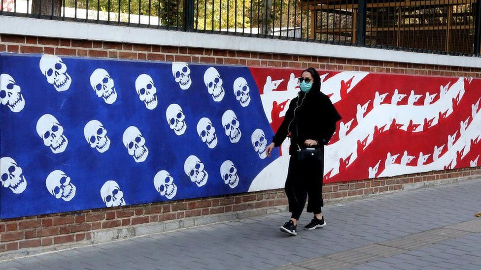 An Iranian woman walks past a mural painted on the outer walls of the former US embassy in Tehran, Iran (4 November 2020), on November 4, 2020 as the US waits for the results of the presidential election