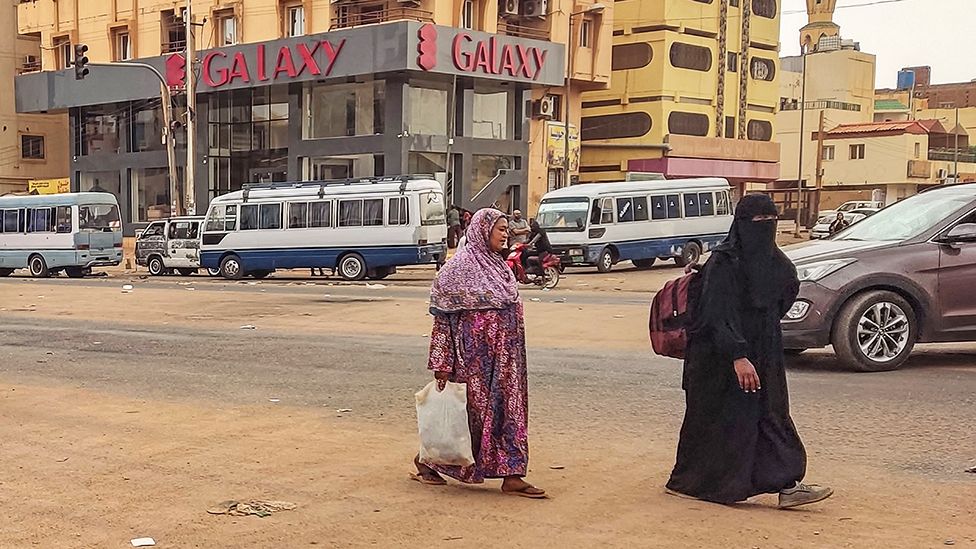 People walk along a street in the south of Khartoum on April 24, 2023