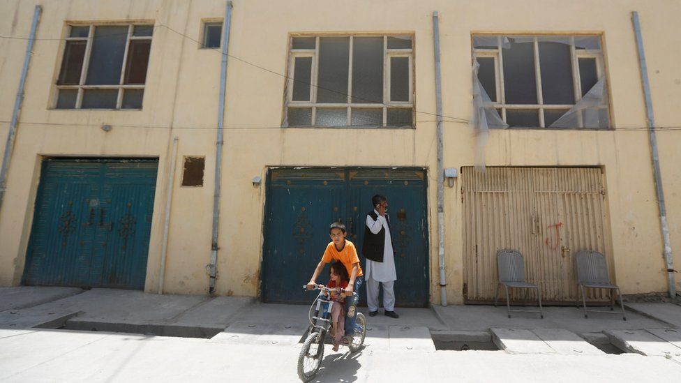 An Afghan boy rides his bicycle in front of a house, where a German aid worker and an Afghan guard were killed last night, in Kabul, Afghanistan May, 2017
