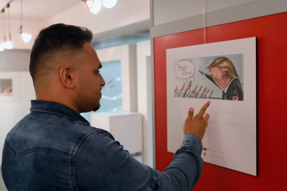 A man looks at cartoons of US President Donald Trump at an exhibition of the Islamic Republic's 2017 International Trumpism cartoon and caricature contest, in the capital Tehran on 3 July 2017