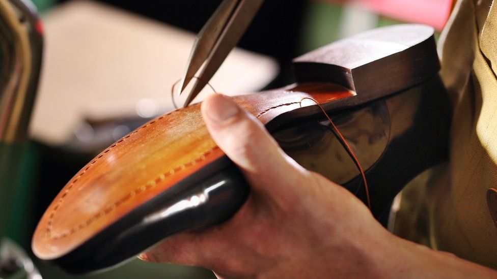 Shoemaker sewing a shoe.