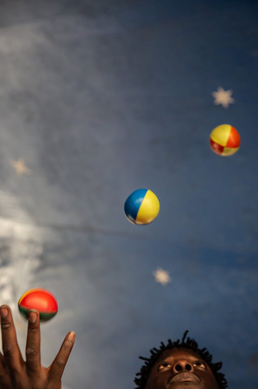 Мужчина жонглирует разноцветными шарами.