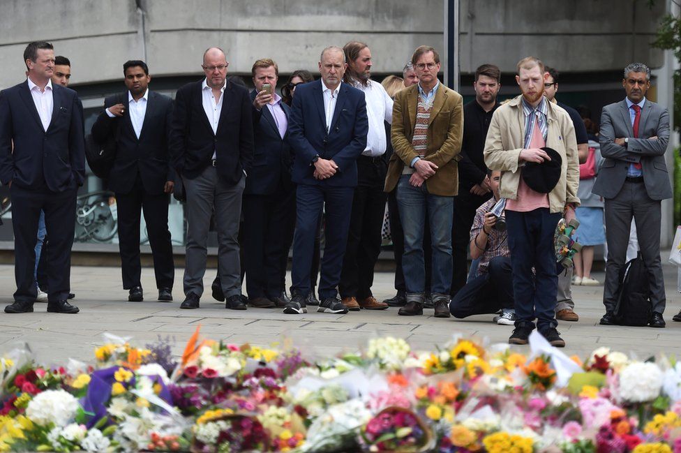 People react as they look at flowers left on the south side of London Bridge near Borough Market