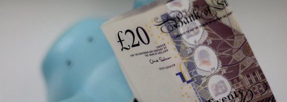 Twenty pound notes in a piggy bank