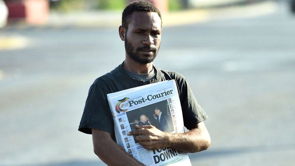 A man sells morning newspapers on a street in Port Moresby