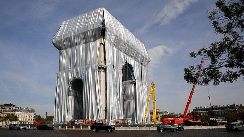 Workers arrange silver blue fabric, part of the process of wrapping the Arc de Triomphe