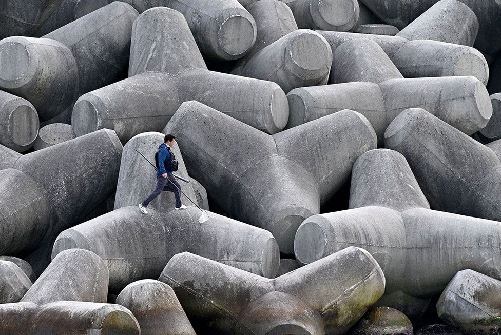An angler walks on concrete tetrapod wave breakers in Gangneung, South Korea