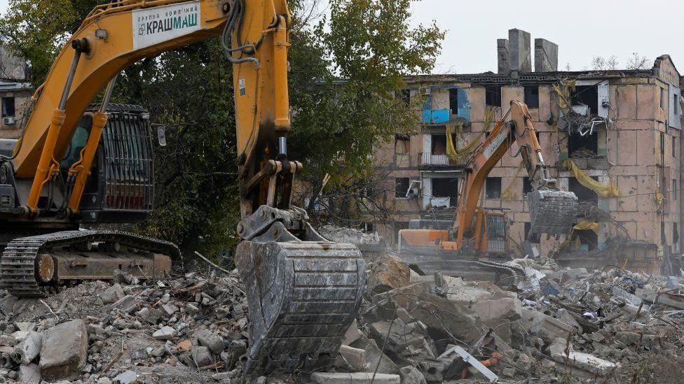 Excavators remove debris of a building destroyed in Mariupol